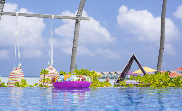 马尔代夫游泳池里明亮的充气游泳圈。热带家庭度假概念图片下载