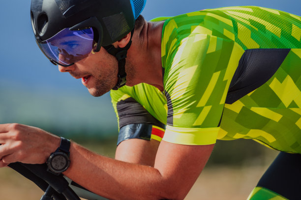 一个穿着运动服、戴着防护头盔骑自行车的铁人三项运动员的特写照片。有选择性的重点图片下载