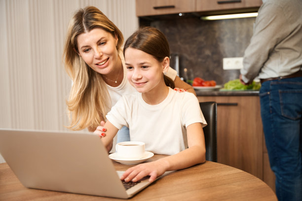 一个女人和一个小女孩在厨房里用笔记本电脑吃饭的照片图片下载