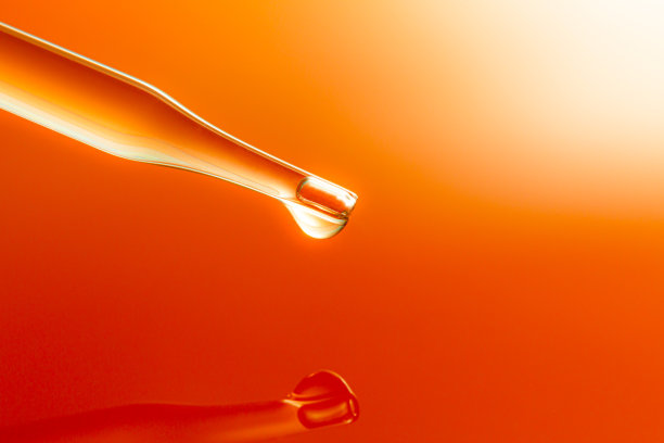 宏观科学实验移液管表面，俯视图微距镜头化学滴管在黄色背景的三个培养皿中的一个中将油注入清澈的液体中，抽象护肤化妆品的配方概念图片下载