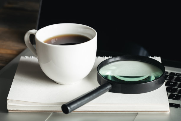 一杯咖啡，放大镜，记事本和笔记本电脑在工作场所，近距离。图片下载