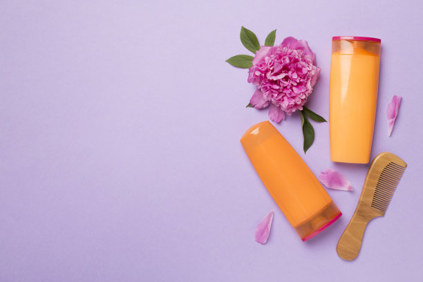 洗发水和护发素与牡丹花和梳子的颜色背景，俯视图图片下载