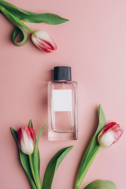 粉色背景上的香水瓶和郁金香。俯视图，平躺，模型图片下载