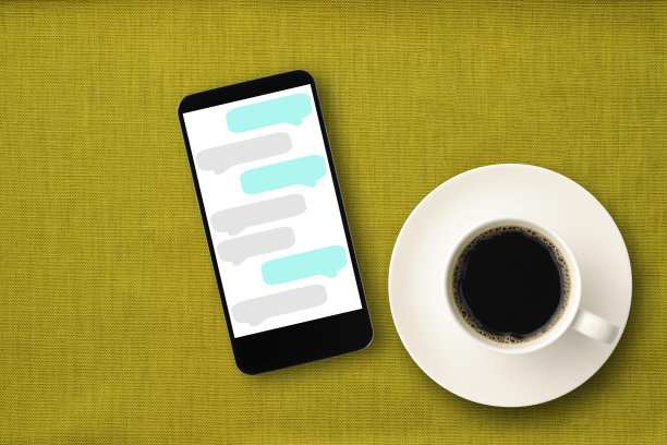 一杯咖啡和智能手机放在绿色的桌布上图片下载