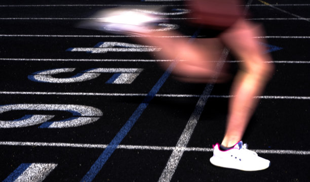 赛跑者在模糊的跑道上越过终点线图片下载