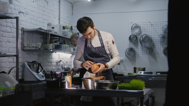 穿着围裙的成年厨师清理工作台图片下载