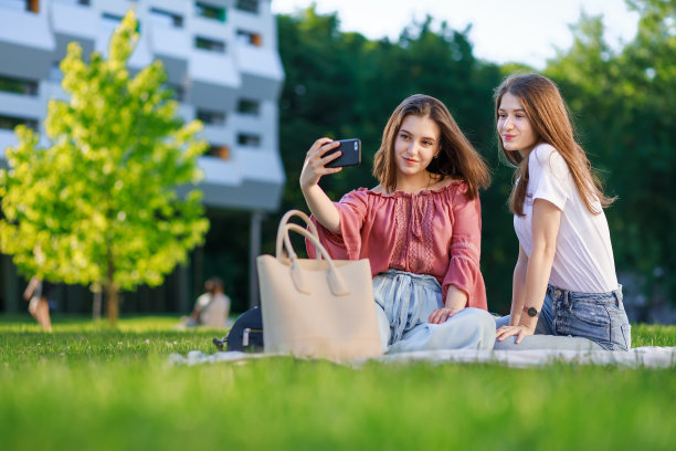 两个女孩坐在公园里，有说有笑图片下载