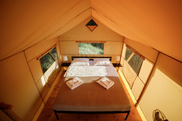 舒适的开放式豪华野营帐篷的内部，在日落时分，里面有灯光。豪华户外露营帐篷，适合夏季度假度假。生活方式的概念图片下载
