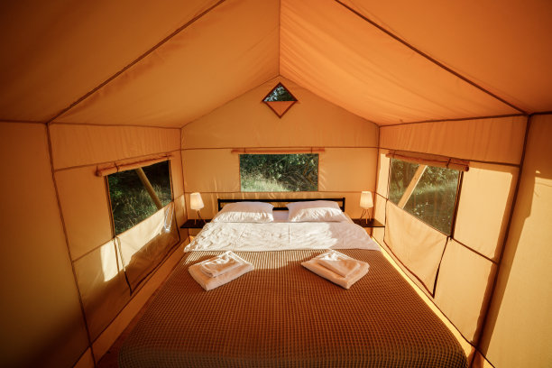 舒适的开放式豪华野营帐篷的内部，在日落时分，里面有灯光。豪华户外露营帐篷，适合夏季度假度假。生活方式的概念图片下载