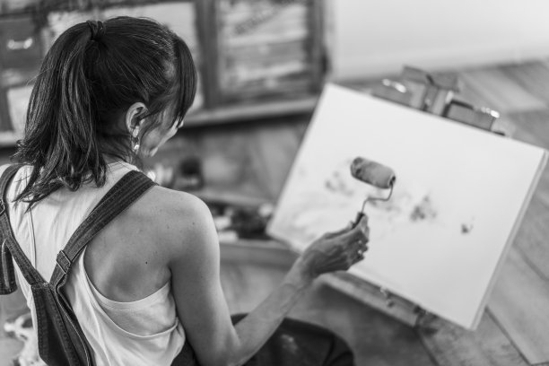 女艺术家在她的艺术工作室地板上的画布上画画。黑色和白色。图片下载