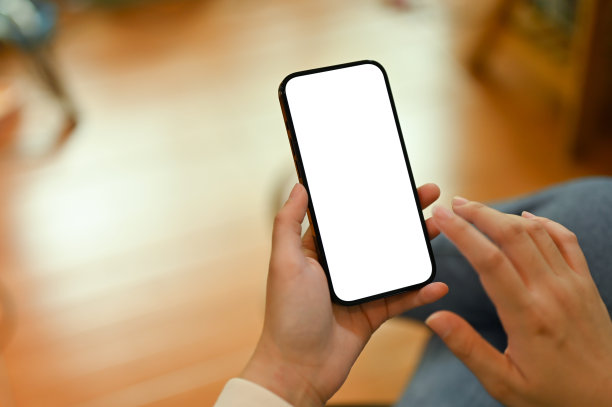 一个女人坐在客厅里玩智能手机的特写照片。图片下载