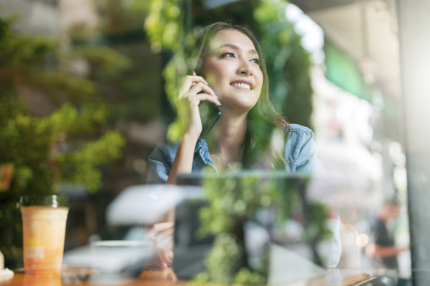 休闲聪明的亚洲女性企业家小型企业在联合办公空间工作手使用智能手机和平板电脑商务谈话咨询拍摄透过窗户玻璃花园反射的观点图片下载