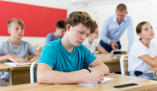 又累又无聊的少年在书桌前睡觉图片下载