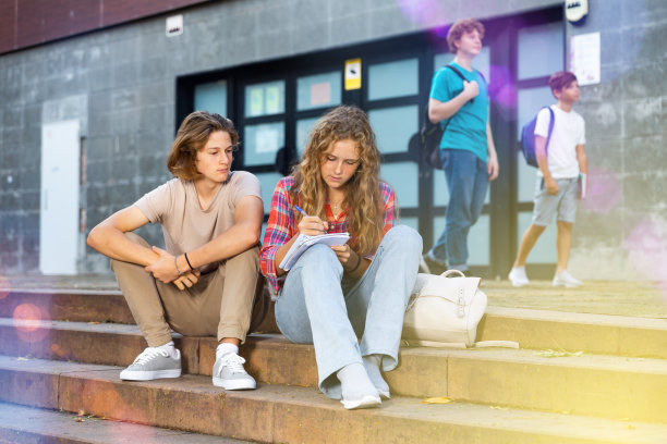 十几岁的男孩和女孩坐在学校附近的台阶上图片下载