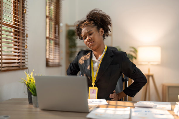 年轻的非洲女性在办公室用笔记本电脑工作时背部疼痛图片下载