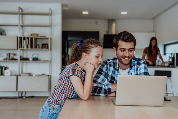 父亲和女儿在现代的房子里，在假期和家人一起在笔记本电脑上聊天。现代家庭的生活图片下载
