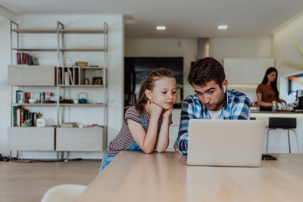 父亲和女儿在现代的房子里，在假期和家人一起在笔记本电脑上聊天。现代家庭的生活图片下载