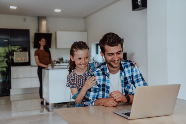 父亲和女儿在现代的房子里，在假期和家人一起在笔记本电脑上聊天。现代家庭的生活图片下载