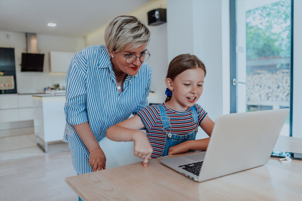 母亲和女儿坐在大房子的现代客厅里，与家人和朋友在笔记本电脑上聊天图片下载