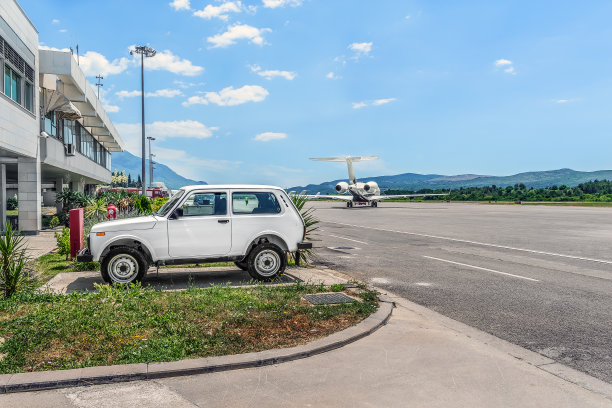 在黑山蒂瓦特机场的跑道上，一辆旧车停在一架飞机的背景上图片下载