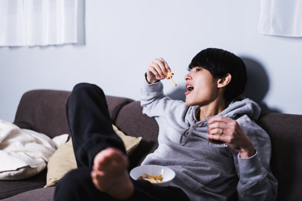 一个一边看电视一边享受酒精和垃圾食品的假期，一个30多岁的懒汉在深夜图片下载
