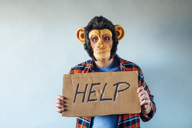 戴着猴子面具的男人手上拿着写着救命的纸板。图片下载