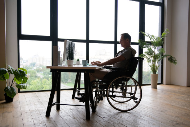 一位坐在轮椅上的老人在办公室的电脑前工作。一个人的剪影图片下载