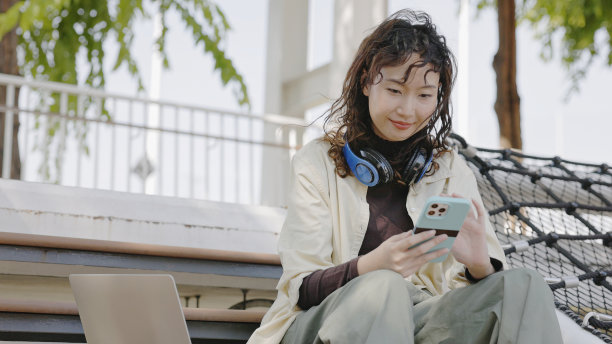 年轻的亚洲女性用触屏智能手机投资网上股票。图片下载