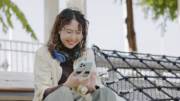 年轻的亚洲女性用触屏智能手机投资网上股票。图片下载