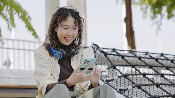 年轻的亚洲女性用触屏智能手机投资网上股票。图片下载