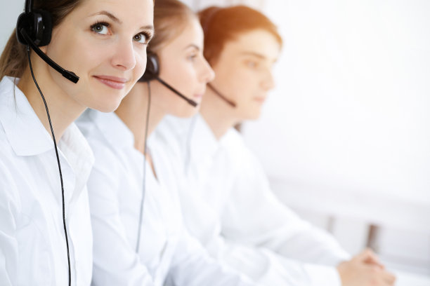 呼叫中心。美丽的年轻女子在阳光明媚的办公室里使用耳机和电脑帮助客户。经营理念图片下载