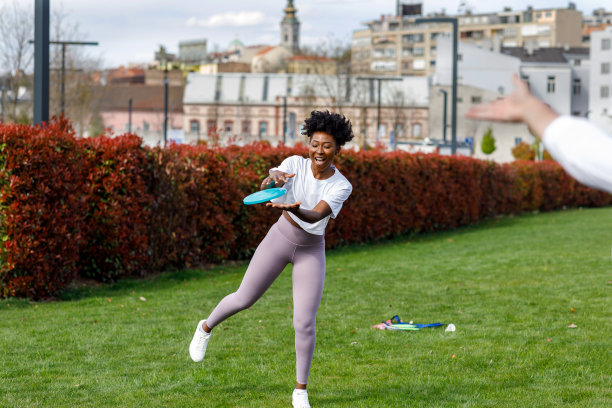 一位年轻的非洲妇女在公园里玩飞盘。图片下载