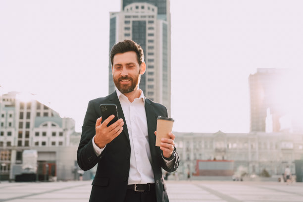 自信的年轻商人在城市里用手机喝咖啡图片下载