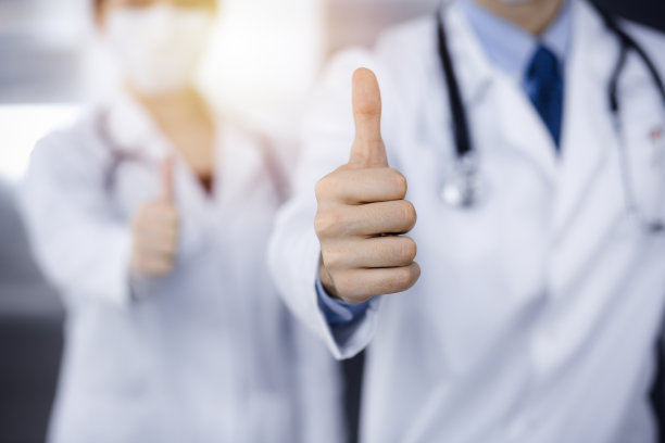 在现代诊所里，不知名的男医生和女医生笔直地站在一起，竖起大拇指表示Ok。医学的概念图片下载