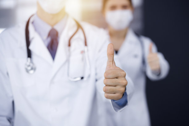在现代诊所里，不知名的男医生和女医生笔直地站在一起，竖起大拇指表示Ok。医学的概念图片下载