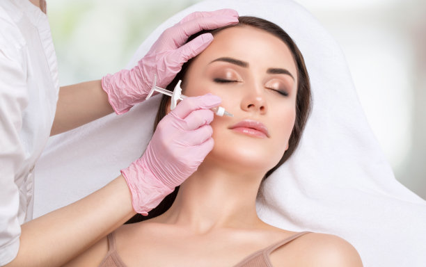 美容师给美女注射丰唇和鼻唇褶皱抗皱。美容院的女性美容。图片下载