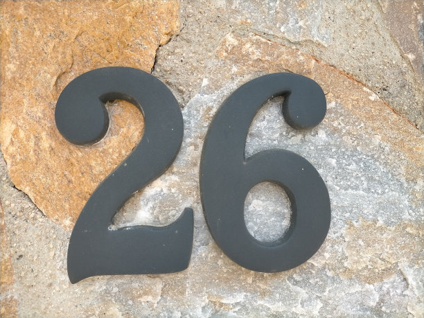 26、二十六个黑色金属数字在光滑的褐色天然石墙上图片下载