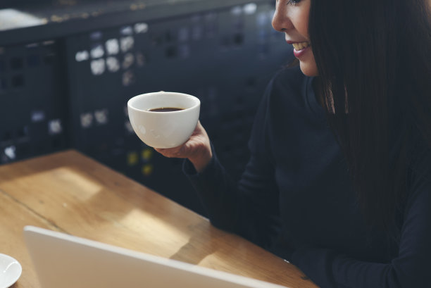 商务女性在办公室喝咖啡。职业女性坐着，享受着早晨的咖啡休息时间。图片下载