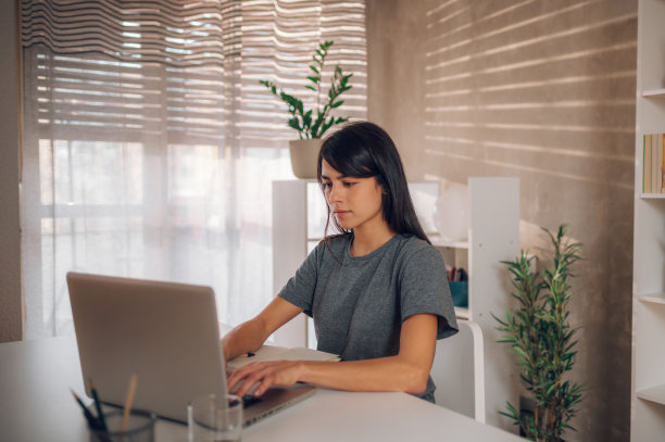 一个白人女商人在她的笔记本电脑上输入电子邮件的侧视图。图片下载