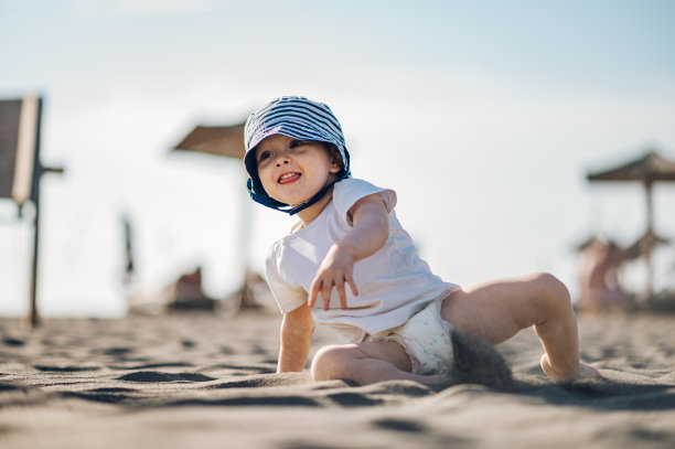 可爱的蹒跚学步的小男孩在沙滩上玩耍图片下载