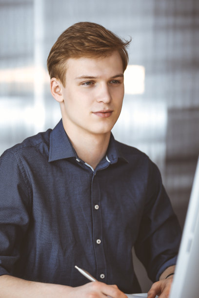 年轻的金发商人用电脑工作。创业意味着努力工作，为成功而奋斗图片下载