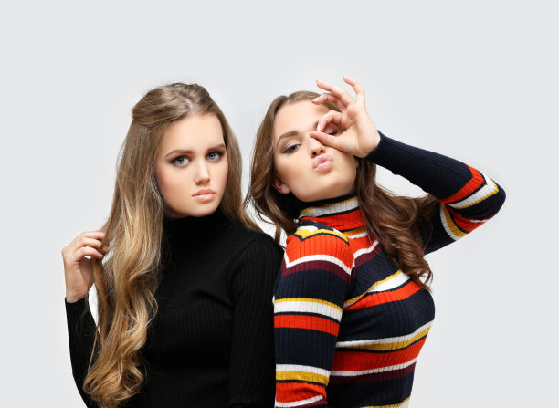 两个穿着毛衣的年轻金发女孩摆姿势，开心地做着鬼脸图片下载