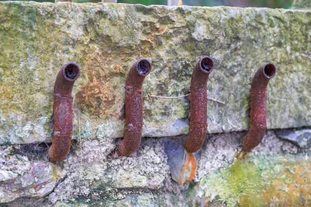 石墙上的水管和管接头陈旧生锈图片下载