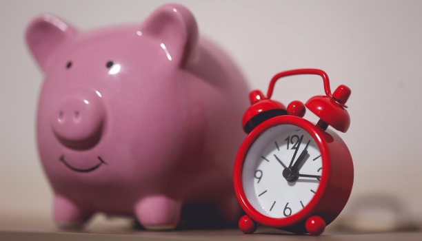 一个存钱罐和一个红色闹钟。金融的概念。图片下载