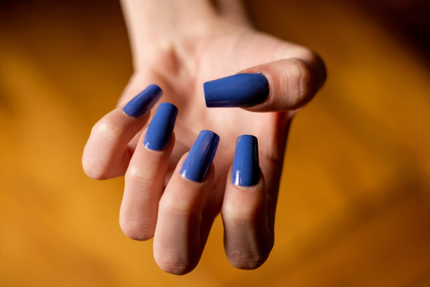 用蓝色的长指甲修指甲。女人的手靠近了。图片下载