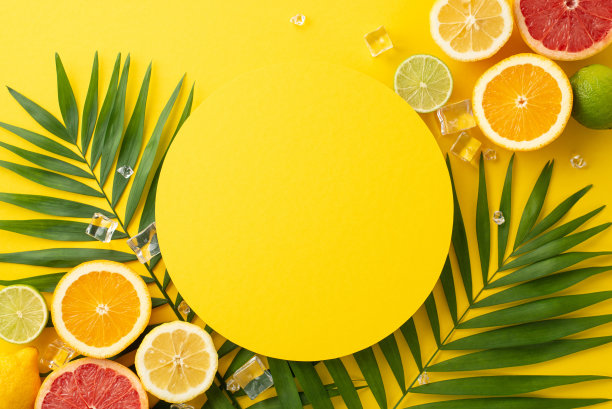 以夏季为主题的平面照片，在阳光明媚的黄色背景上，大量的柑橘类水果，橙色，柠檬，酸橙和葡萄柚，新鲜的绿色棕榈叶和一个空白的圆圈，用于文字或品牌图片下载