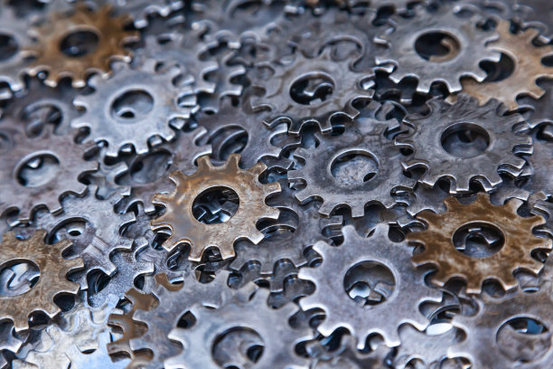 许多新的钢齿轮在油的特写。图片下载