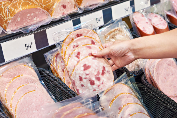 一名妇女在商店挑选香肠和火腿图片下载