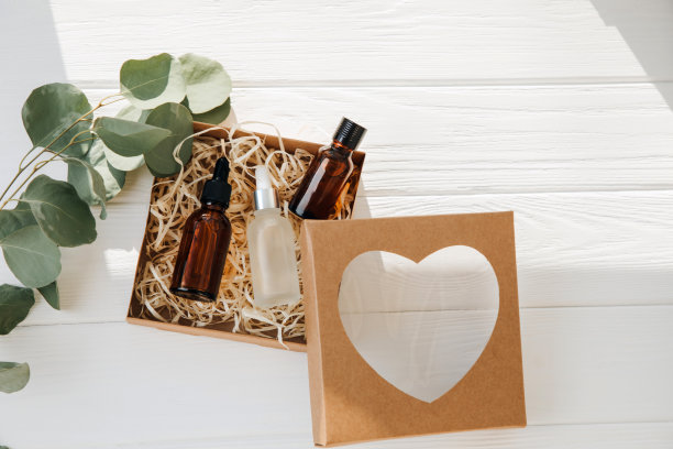 一个装在环保纸板包装里的礼物，里面有白色木制背景的化妆品图片下载