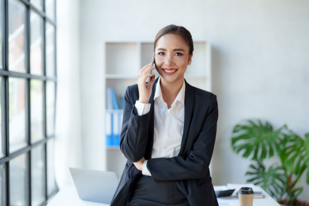 漂亮的亚洲女商人站在电话里友好地向办公室的客户解释各种任务。图片下载